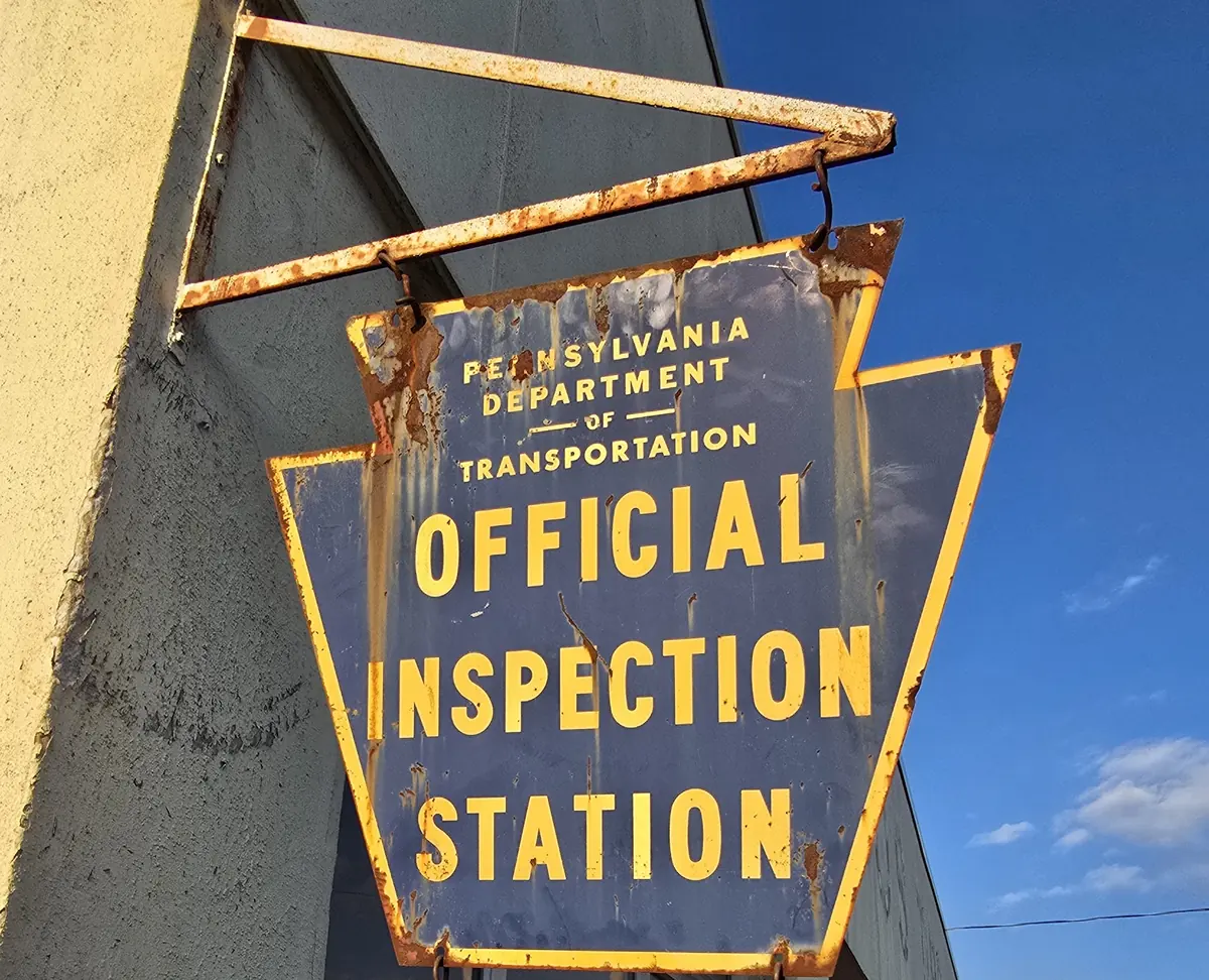 The Pennsylvania Department of Transportation Official Inspection Station sign mounted on the building at Cutts and Bruises
